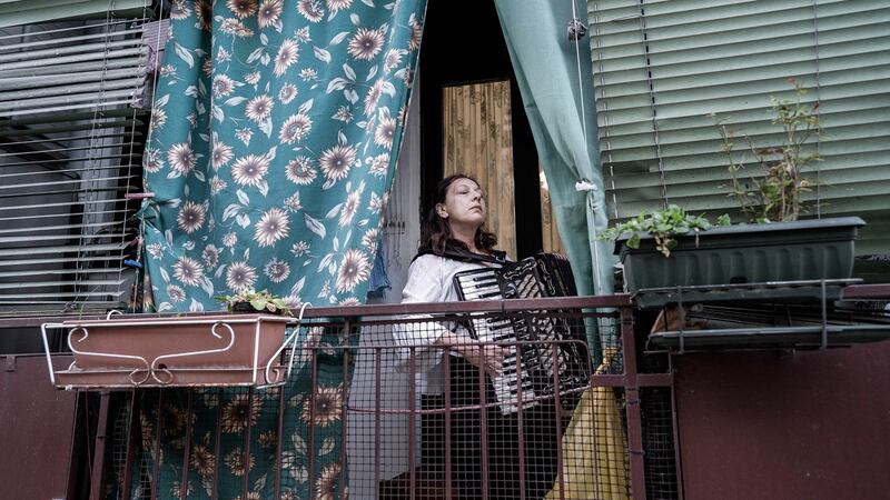 A woman plays music from her balcony in Milan. Photograph: New York Times