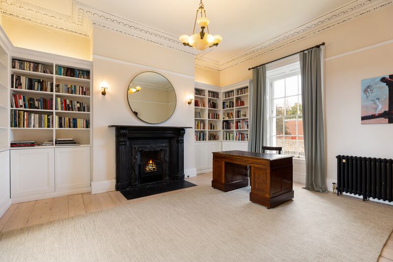 To the right of the hall is a fine study with dual aspect, a fireplace and bespoke bookshelves.