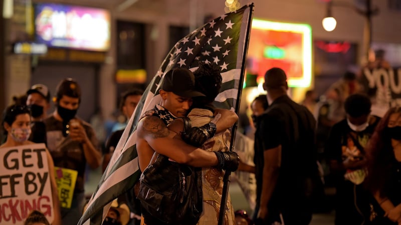 Two men embrace next to a makeshift memorial in honour of the victims of police brutality, during a demonstration against racism, in Hollywood, California on Sunday.  Photograph: Agustin Paullier/AFP via Getty Images