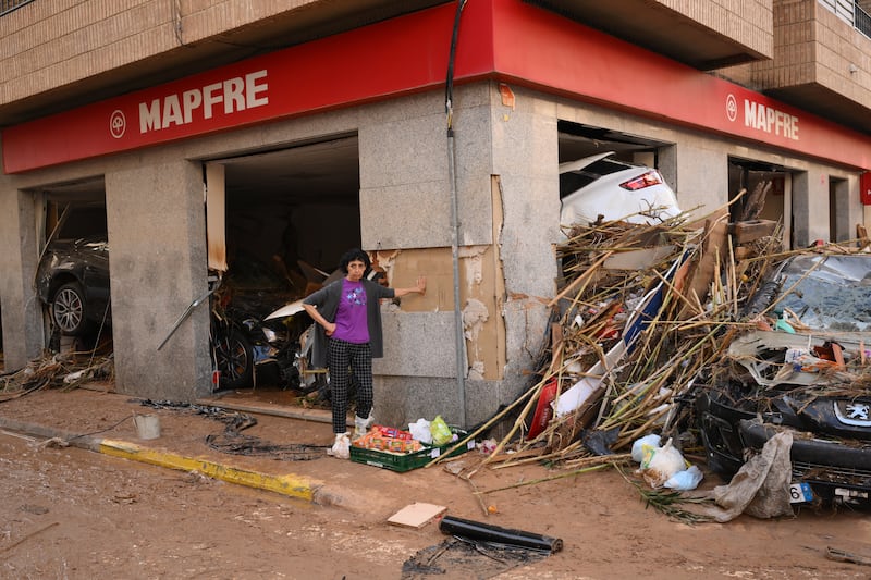 A woman stands near a building damaged by debris and floating cars after flooding hit large parts of the country. Photograph: David Ramos/Getty Images