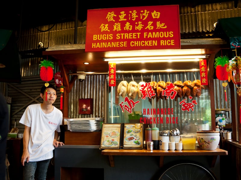 Singapore, Singapore - January 21, 2012: Foodstall selling chicken and rice in Singapore. Chinese New Year decorations. The vendor is standing next to his stall.