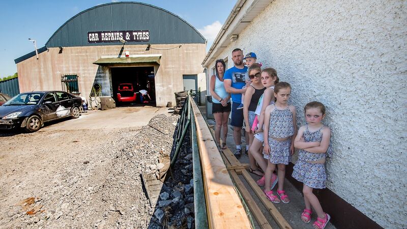 John Paul Doyle with his wife Frances and five of their six children  in the back garden of a house offered to them by Longford County Council. The house is adjacent to a working garage with  a large petrol station across the road. Photograph: Brenda Fitzsimons/The Irish Times