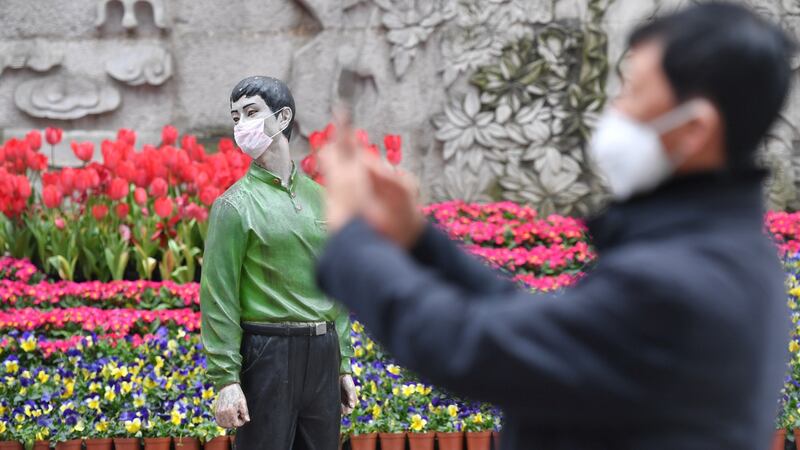 A man takes pictures near a statue with a face mask on in Chengdu, Sichuan province, China. Photograph: cnsphoto via Reuters