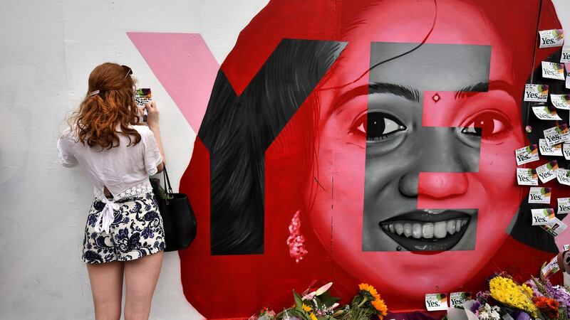 A woman writes a note on the Savita Halappanavar mural in Portabello, Dublin on Saturday. Photograph: Charles McQuillan/Getty