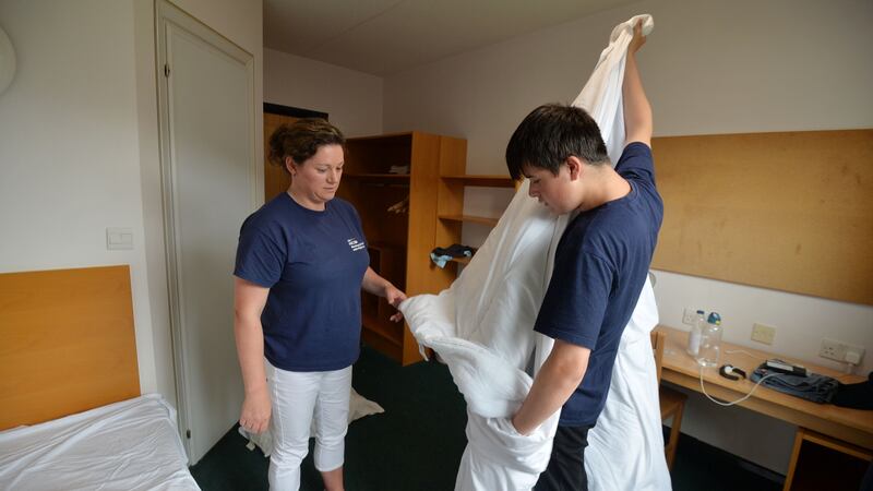 Lawrence Noonan learning bed-making skills from Caroline Lane at a NCBI residential summer camp. Photograph: Alan Betson / The Irish Times