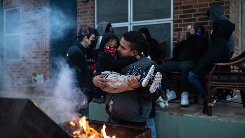 Eric Traugott warms up his young son, Eric Traugott Jr., beside a fire made from a discarded wooden armoire outside of their apartment in Austin, Texas, that remains without power on Wednesday. They’ve been without power since early Monday morning. Photograph: Tamir Kalifa/The New York Times