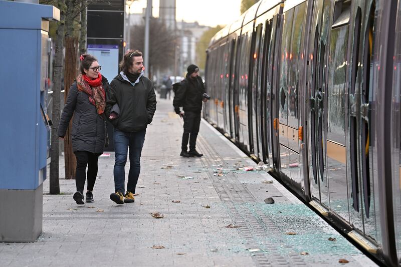 People walk past a destroyed Luas tram on Friday morning on O'Connell Street. Photograph: Charles McQuillan