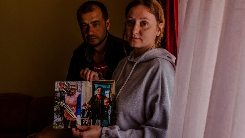 Tetiana Naumova and her husband, Vitaliy, with photographs of her parents, Lidiya and Serhiy Sydorenko, who were killed by Russian troops, in Bucha, Ukraine. Photograph: Daniel Berehulak/The New York Times