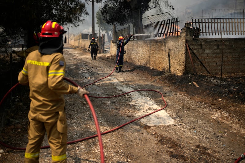 Firefighters tackle flames at a house in Acharnes, north of Athens. Photograph: Thanassis Stavrakis/AP