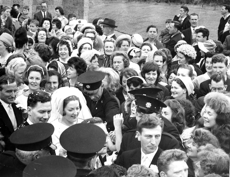 Gay Byrne and Kathleen Watkins being helped through a crowd of about 300 people who surrounded the couple when they left the Church of the Nativity, Saggart, Co Dublin, after their wedding in June 1964. Photograph: Gordon Standing/The Irish Times