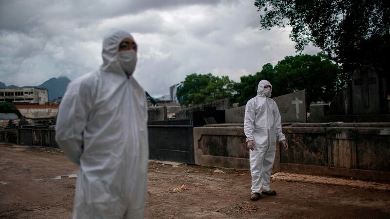 Undertakers wait for the body of a Covid-19 victim at the Caju cemetery in Rio de Janeiro, Brazil. Photograph:  Mauro Pimentel/AFP via Getty Images