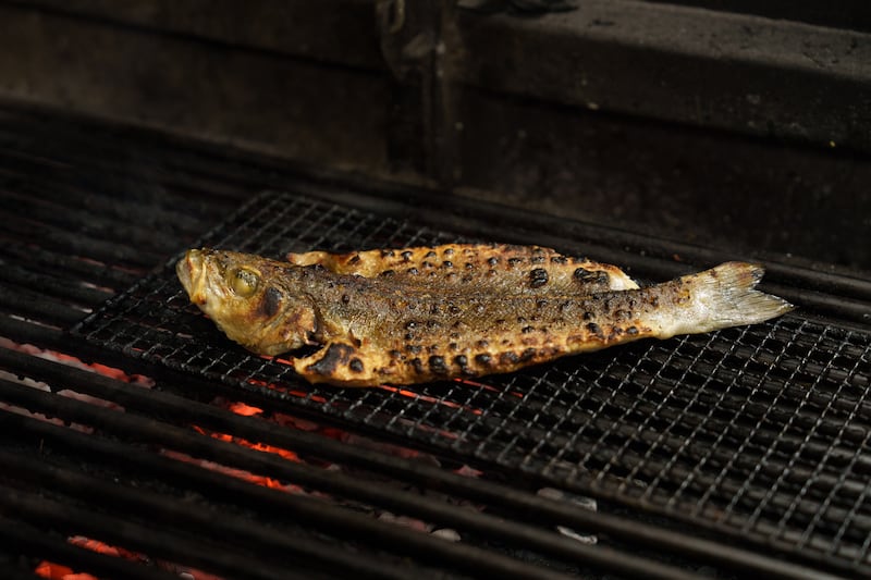 Whole seabass cooking over charcoal at Achara. Photograph: Fran Veale 