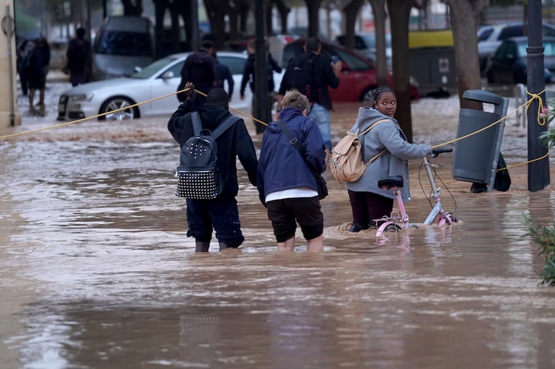 People walk through flooded streets in Valencia. Photograph: Alberto Saiz/AP