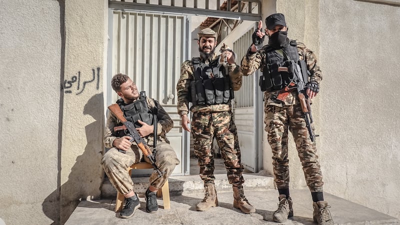 Rebel fighters, including Alaa Ogit (far right), pose outside a school they have turned into a base in Hama. Photograph: Sally Hayden. 