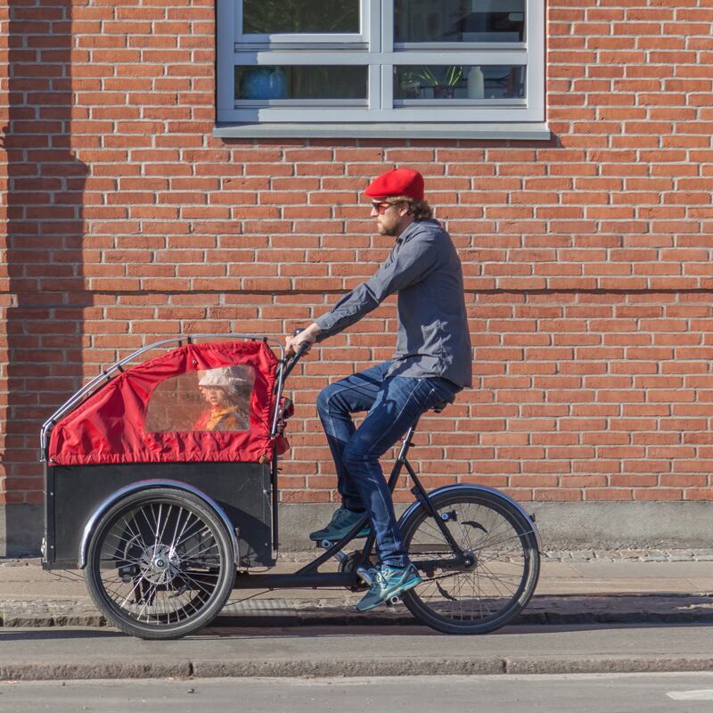 Smiling parents cycling their children around in waterproof war chariots. Photograph: iStock