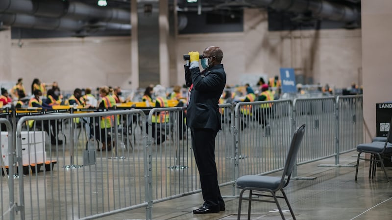 An official poll watcher uses binoculars as workers count ballots for the US presidential election at the Philadelphia Convention Center in November 3rd. Photograph: Hannah Yoon/Bloomberg