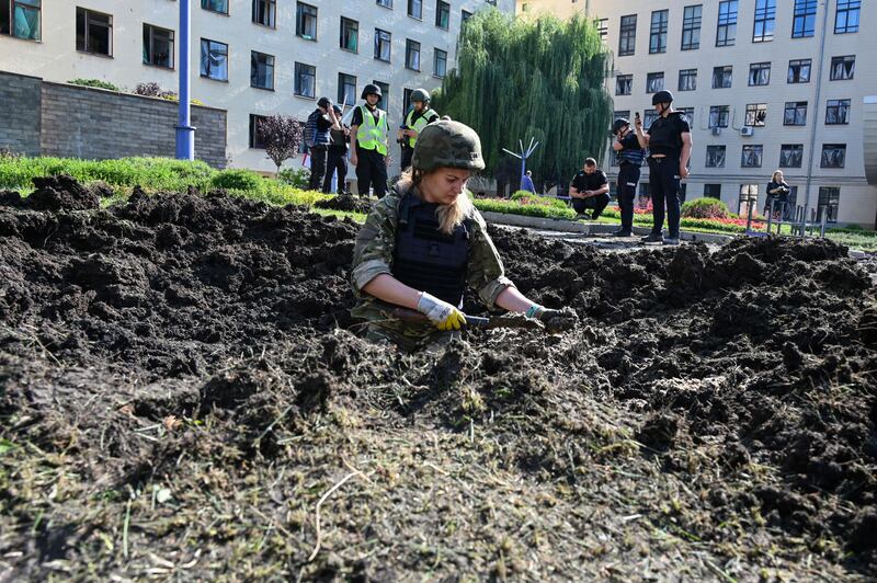 Police experts inspect a crater caused by a shell explosion outside the National University of Urban Economy in Kharkiv. Photograph: Sergey Bobok/AFP/Getty Images