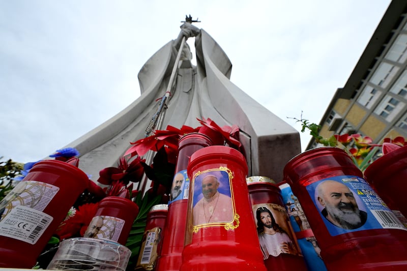 A candle with a portrait of Pope Francis is set at the bottom of a statue of Pope John Paul II at the Gemelli hospital, where the pontiff is being treated for pneumonia. Photograph: Tiziana Fabi/AFP