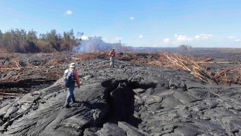 Hawaii Volcano Observatory (HVO) geologists walk over the surface of a lava flow from the Kilauea Volcano to track surface breakouts near the village of Pahoa. Photograph via Reuters