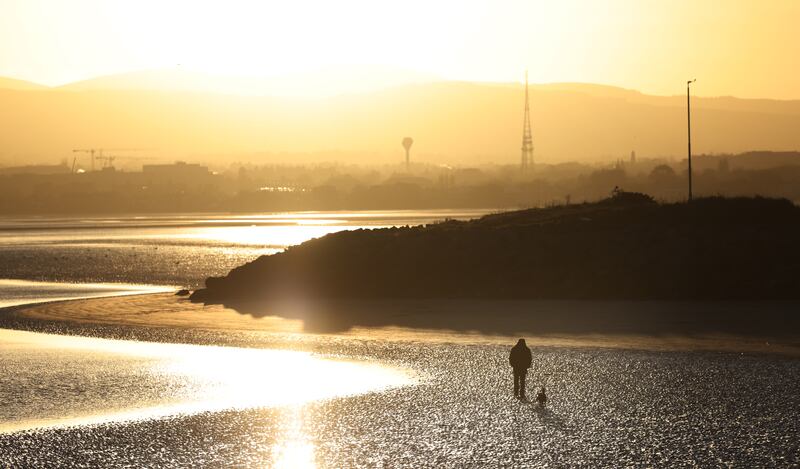 A man walks his dog as a low winter sun descends towards dusk on Sandymount strand in Dublin. Photograph: Bryan O’Brien/The Irish Times

