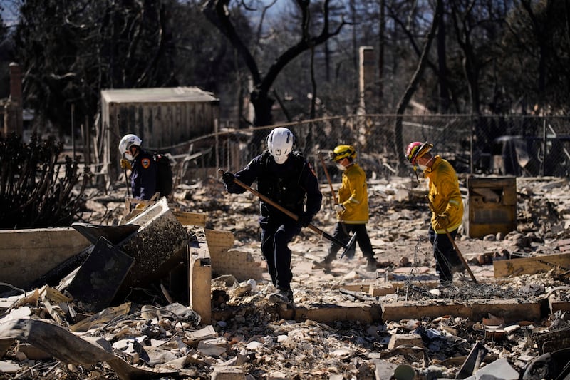 A search-and-rescue crew sifts through the wreckage of a home destroyed by the Eaton fire in Altadena, California. Photograph: John Locher/AP