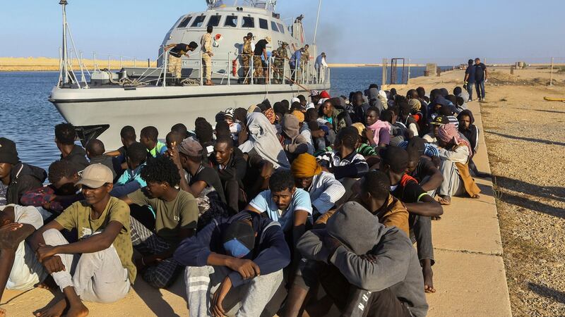 Rescued migrants are seated next to a coastguard boat in the city of Khoms, Libya, in 2019. Photograph: Hazem Ahmed/AP Photo