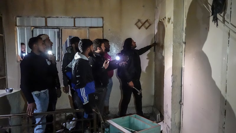 A man attempts to break down a wall in Sednaya prison, as families searched for missing loved ones