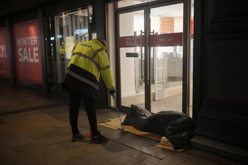 A man sweeps next to a homeless man in the early morning on Henry Street in Dublin during this week's cold weather. Photograph: Chris Maddaloni
