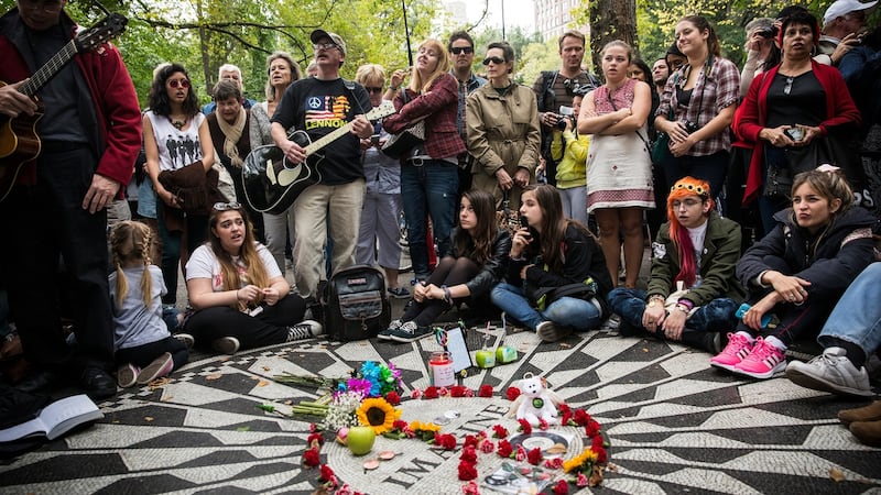 Fans of John Lennon sing songs  around the “Imagine” tile mosaic in the Strawberry Fields section of Central Park, New York. Photgraph: Andrew Burton/Getty Images