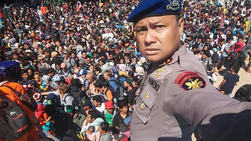 Chief of the Marine Police of Lombok, Dewa Wijaya takes a picture in front of hundreds of local and foreign tourists gathering on the beach after an earthquake. Photograph: EPA