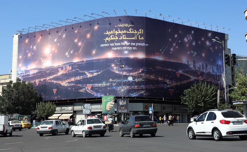 Iranians drive near an anti-Israeli billboard depicting recent Iran's missile attack on Israel and a sentence reading in Persian 'If you want war, we are the master of war', at the Enghelab square in Tehran on Thursday. Photograph: Abedin Taherkenareh/EPA