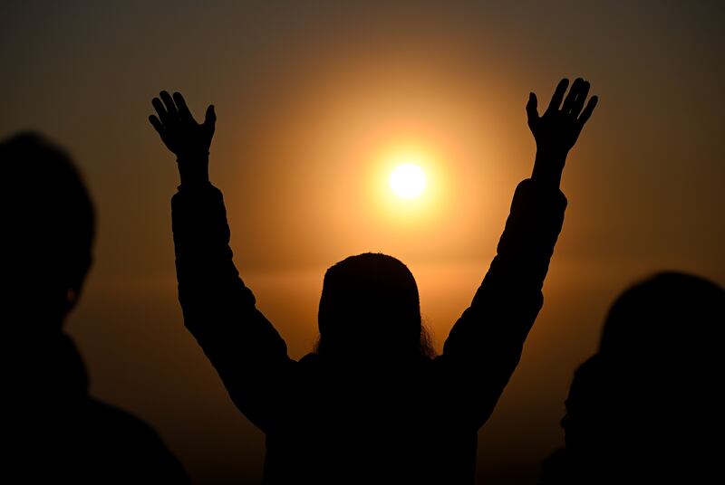 A person raises their arms to welcome the sun at Stonehenge on June 21, 2023 in Wiltshire, England. Photograph: Finnbarr Webster/Getty Images)