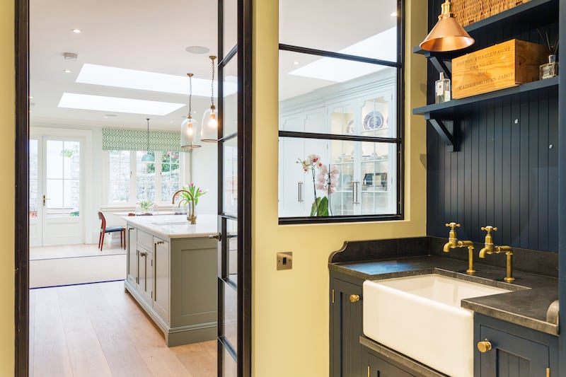 The view from pantry to kitchen featuring butler's sink, brass taps and primrose yellow-coloured sliding door