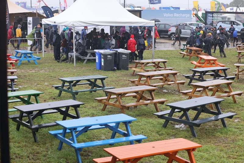 Visitors eat under a gazebo next to empty picnic tables during a downpour. Photograph: Dara Mac Dónaill/The Irish Times