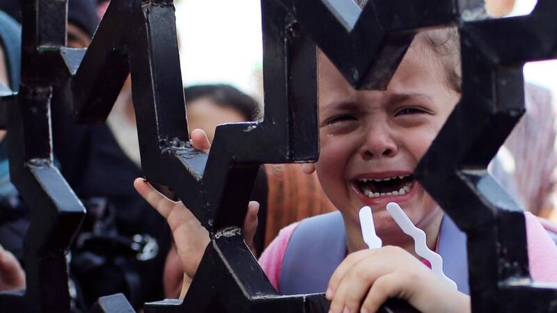 A Palestinian child standing behind the gate of Rafah crossing cries as he tries to cross into Egypt with his family, in the southern Gaza Strip. Photograph: Ibraheem Abu Mustafa/Reuters