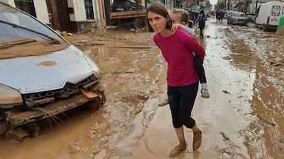 Christine Connolly carries her four-year-old daughter Yasmin through the floods in Massanassa near Valencia last week.