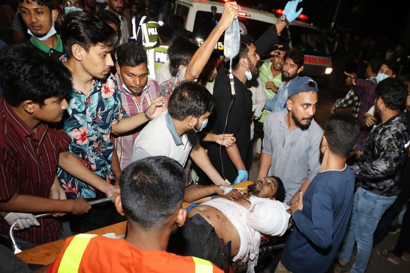 Rescue workers and civilians carry an injured victim to a hospital after a fire broke out at a container storage facility in Chittagong