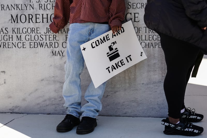 People lean against the base of a statue of Martin Luther King jnr at Morehouse College, Atlanta, before a march to protest against Georgia's Senate Bill 202 election law. Photograph: Elijah Nouvelage/AFP via Getty Images