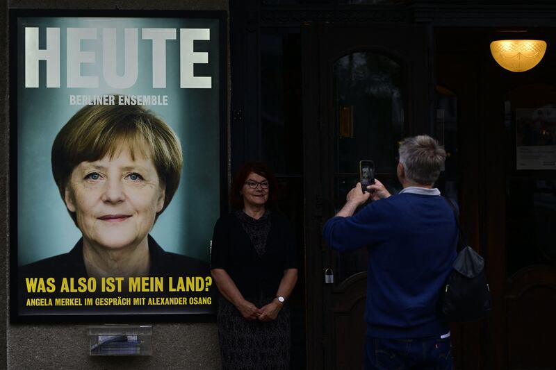 A woman poses next to a poster with former German chancellor Angela Merkel announcing her first public interview since stepping down. Photograph: John MacDougall/AFP via Getty Images