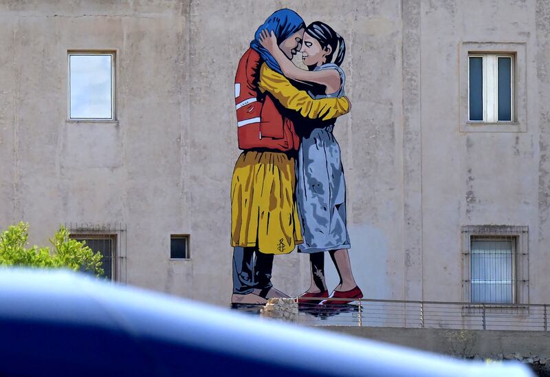 A mural by street artist Laika titled 'Rise up together!' shows two women embracing on the facade of the Migration Museum, on the island of Lampedusa, south of Sicily. Photograph: Tiziana Fabi/AFP