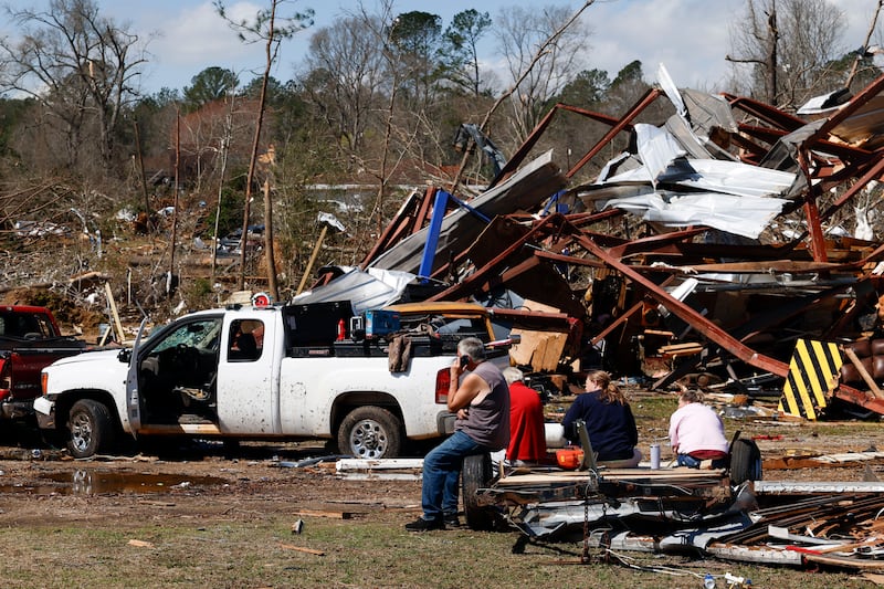 Friends and family members take a break as they search for belongings in the damage after a tornado passed through Plantersville, Alabama. Photograph: Butch Dill/AP