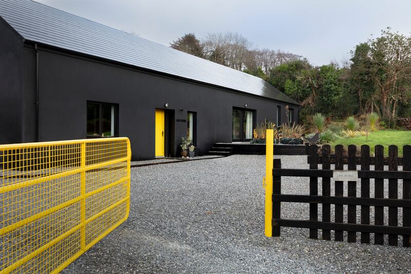 The exterior of the bungalow painted in blackbird colours, with the five-bar gate similarly liveried and customised to try and stop the deer getting in and eating their early-stage garden