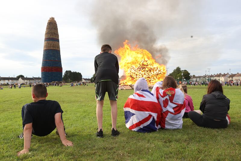 People gather at the Craigyhill bonfire in Larne, prior to it being lit on the Eleventh Night to usher in the Twelfth commemorations. Photograph: Liam McBurney/PA