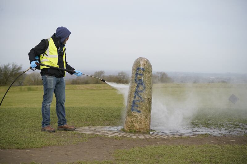 A worker from the office of public works begin the clean up of graffiti on the Lia Fáil standing stone. Photograph: Niall Carson/PA