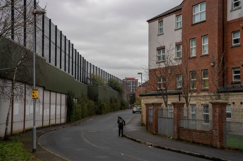 A student walks home from school next to a so-called peace wall that divides the Protestant and Catholic communities of Shankill Road and Falls Road in west Belfast. Photograph: Andrew Testa/The New York Times
                      