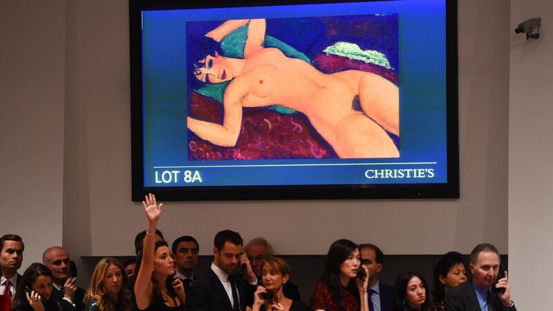 Bid takers stand in front of a video screen with Amedeo Modigliani’s Nu couche during the sale. Photograph: Timothy A Clary/AFP/Getty Images