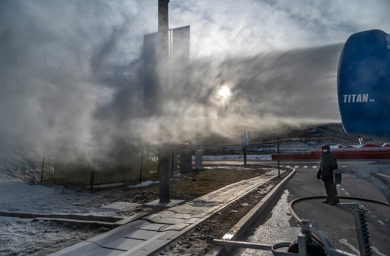 A worker stands next to a snow machine making artificial snow outside one of the athletes villages for the Beijing 2022 Winter Olympics before the area closed to visitors in Chongli county, Zhangjiakou, Hebei province, northern China. Photograph: Kevin Frayer/Getty Images