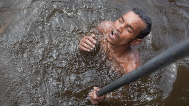 A sand miner comes up for air after a dive at the Vasai creek in Bhiwandi, Thane, India. Photograph: Thomson Reuters Foundation