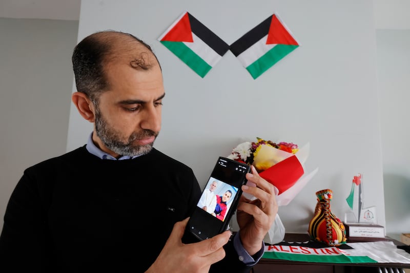 Dr Abumarzouq holds a phone with a photo of his father Faisal and his younger brother Ahmed Abumarzouq, who was killed last year in Gaza. Photograph: Alan Betson