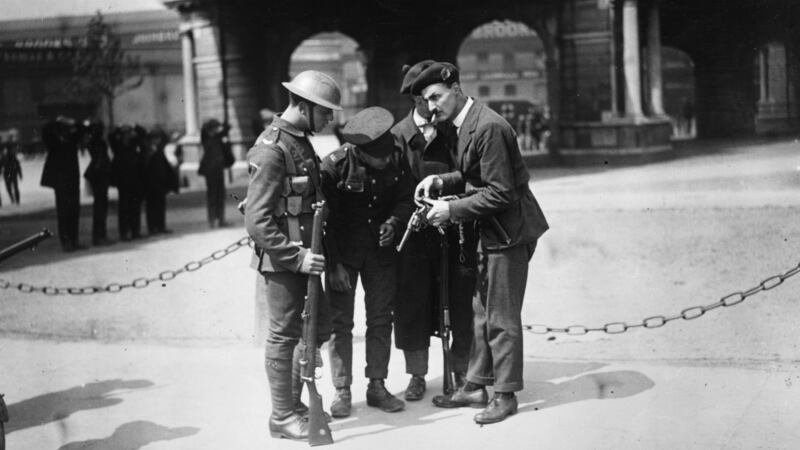 British soldiers watch a member of the Black and Tans, an armed auxiliary force of the Royal Irish Constabulary, reload his .45 revolver, after the burning of the Custom House in Dublin (headquarters of the British Civil Service in Ireland). Photograph:  Walshe/Getty Images